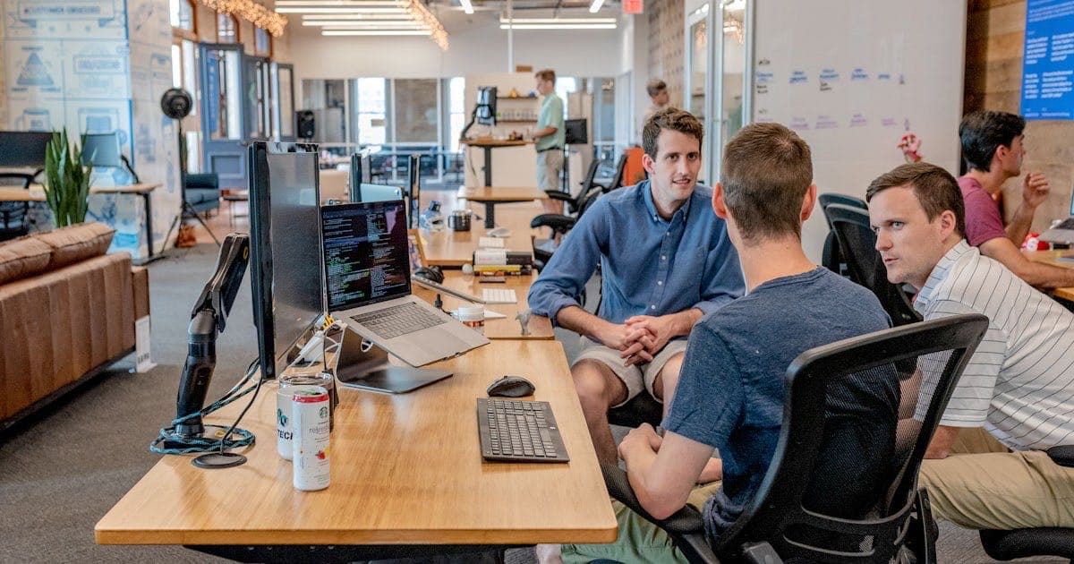 Team comparing CRM platforms in a modern workspace with laptops and dashboards