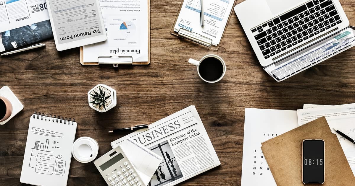 Moderner Arbeitsplatz mit Laptop, Notizbuch und Kaffee, der für KI-Tools steht, die Inhabern kleiner Unternehmen 2026 helfen, Zeit zu sparen