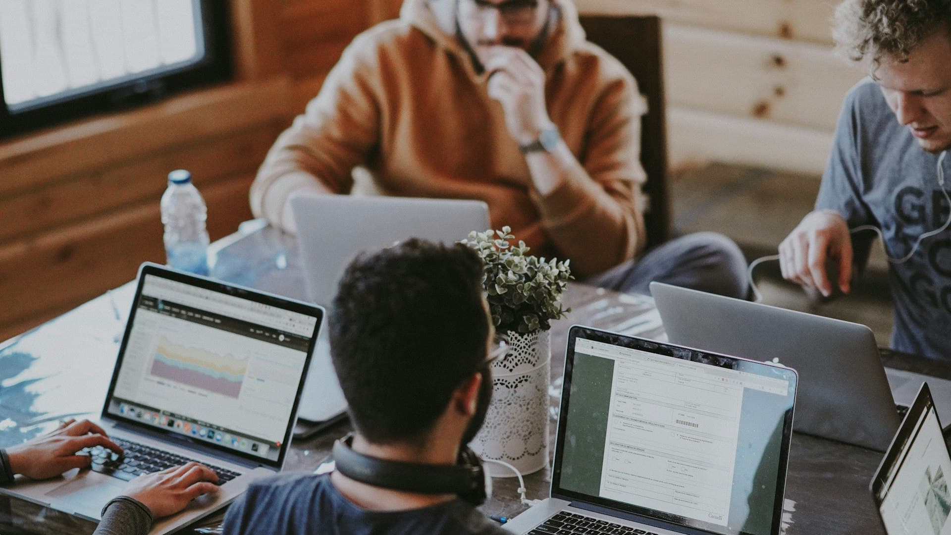 Современная распределённая команда сотрудничает вокруг ноутбуков с живыми дашбордами в светлом рабочем пространстве