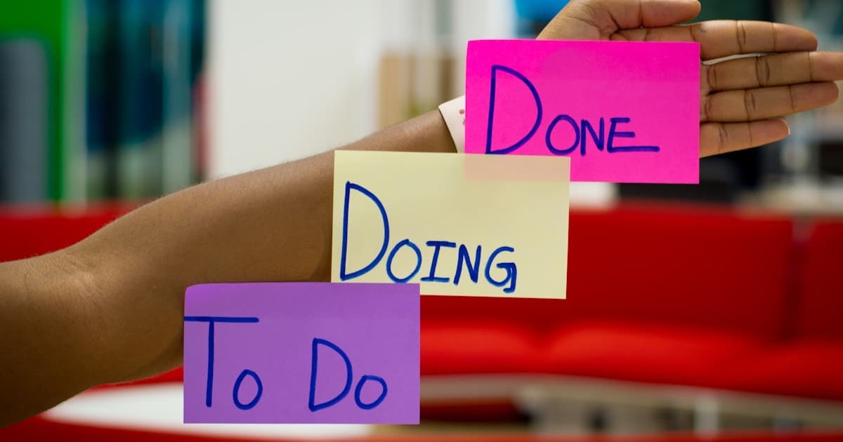 يد تحمل ملاحظات لاصقة To Do, Doing, Done على ذراع - تمثل فلسفة كانبان البسيطة في قلب قرار ClickUp مقابل Trello