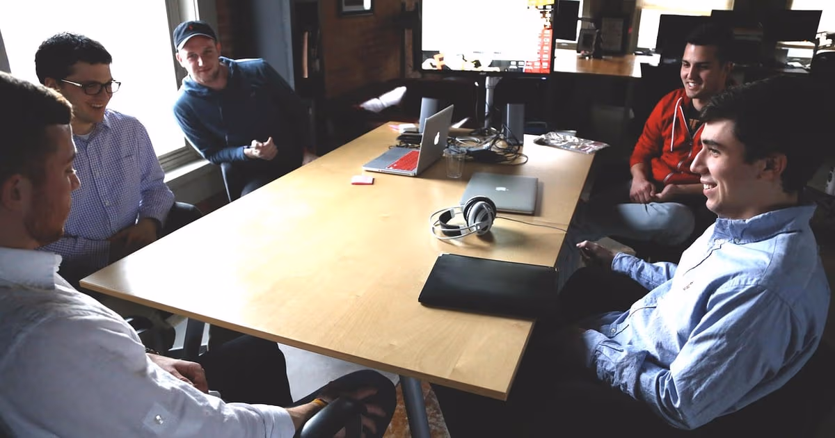 Small support team at a shared desk answering customer emails and WhatsApp chats on laptops, representing Help Scout alternatives in 2026
