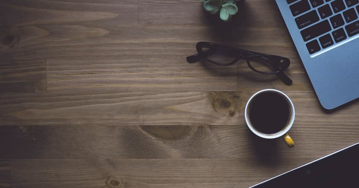 Postazione di lavoro con laptop e caffè su una scrivania, simbolo delle moderne alternative a Trello per i team in crescita nel 2026