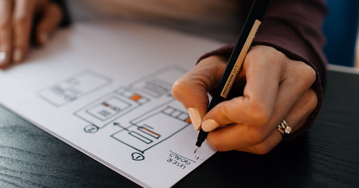 Hand sketching user goals and workflow boxes on paper - representing the sprint planning decision between ClickUp and Jira