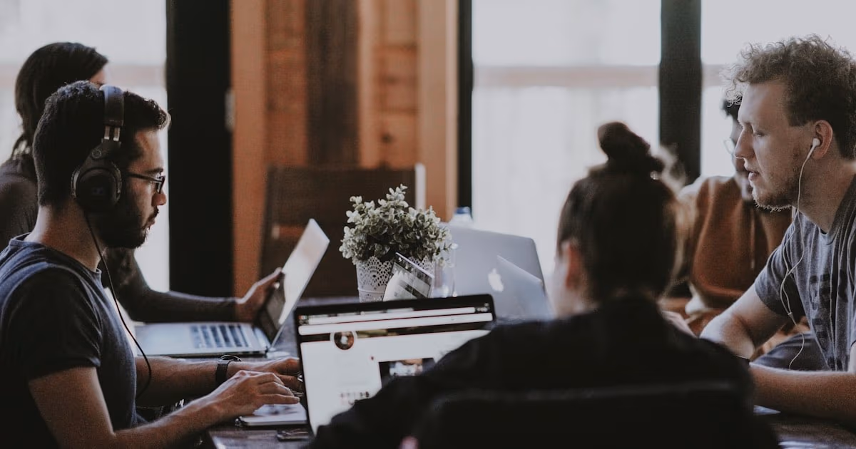 Team moderno che lavora a un tavolo condiviso con i portatili - a rappresentare la decisione ClickUp vs Monday.com per un piccolo team