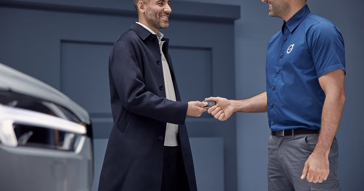 Vendedor de concesionario mostrando un vehículo a un cliente en el salón de exposición